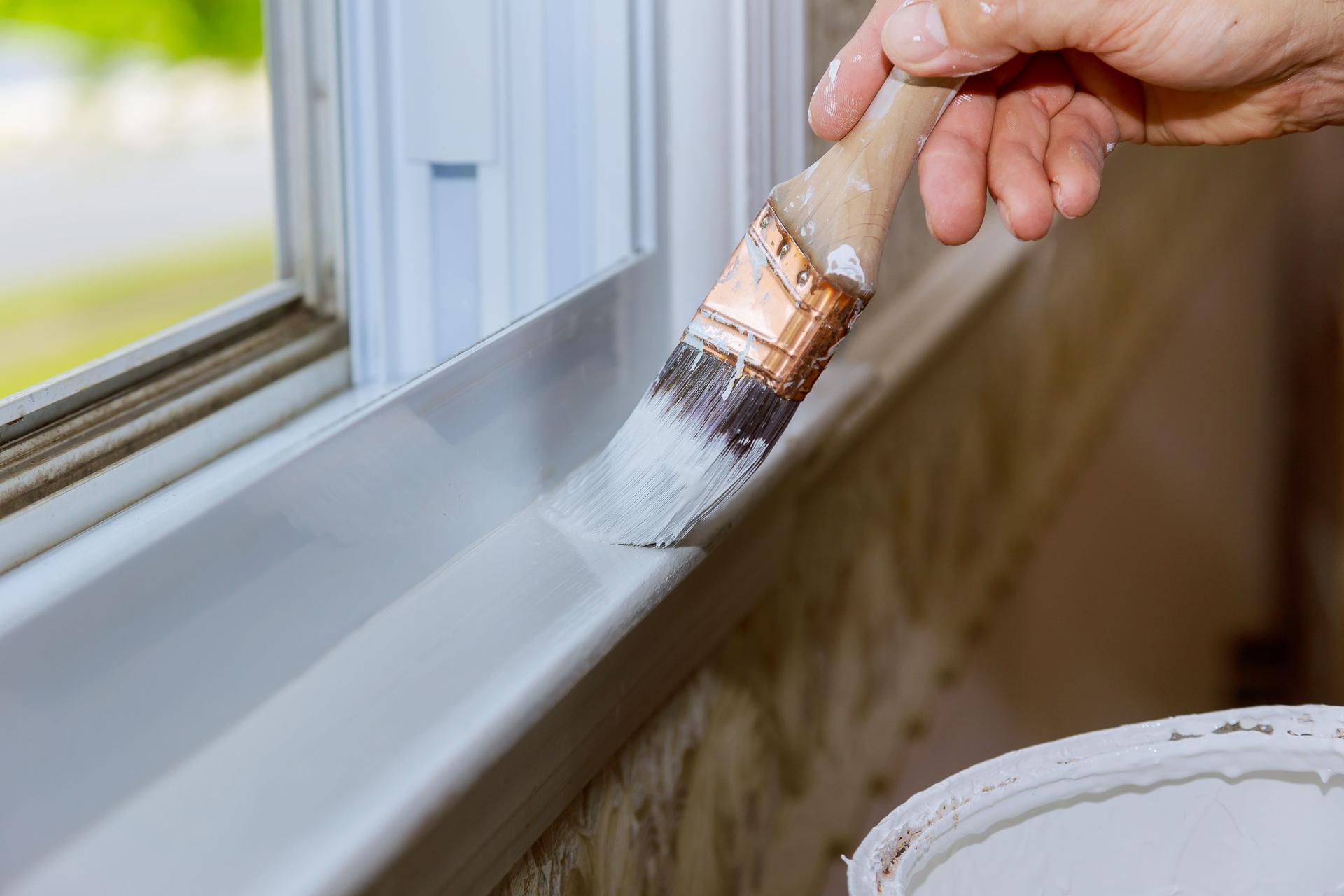 Close up of man hand carefully painting the edge of an house window