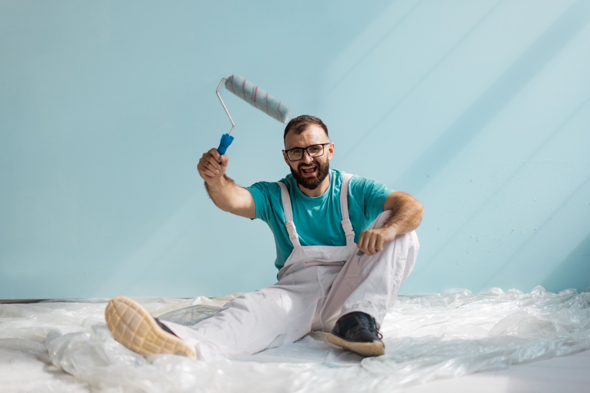 Man cheerfully holding paint roller for renovation